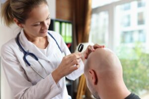 Dermatologist inspecting man's head for skin cancer