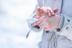 Person applying cream to psoriasis on hand in the winter time.